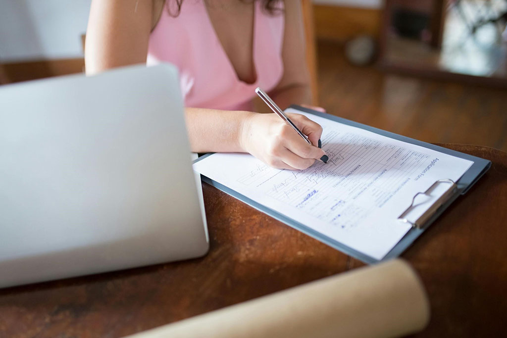 Person filling out dental patient form on clipboard