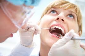 Woman looking up with mouth open as dentist checks gums
