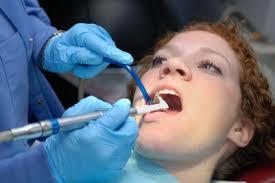 Woman with mouth open as dentist cleans mouth