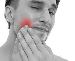 Black and white photo of man holding cheek with glowing red pain area